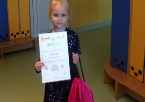 Dziewczynka z dyplomem i nagrodą za udział w konkursie.